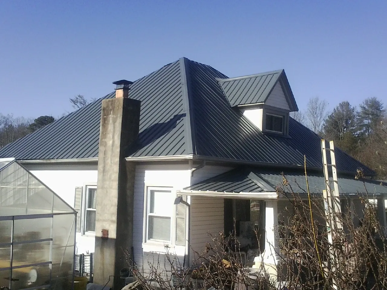 Dark blue standing seam metal roof on a white farmhouse with dormer — Slate & Tile Roof Repair by Roofing Brothers in Orofino