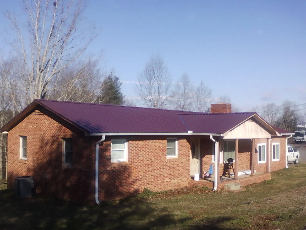 Burgundy metal roof on a brick ranch home with a new addition in Orofino
