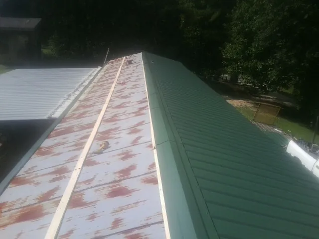 Old rusted panels beside newly installed green metal roofing — Wind Damage Roof Repair by Roofing Brothers in Orofino