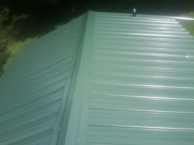 New green metal panels meeting at the ridge of a roof — Flat Roof Repair work by our crew in Orofino