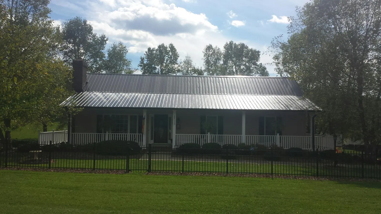 Gray metal roof on a brick ranch with a full width front porch — Gutter Guard Installation work by our crew in Orofino