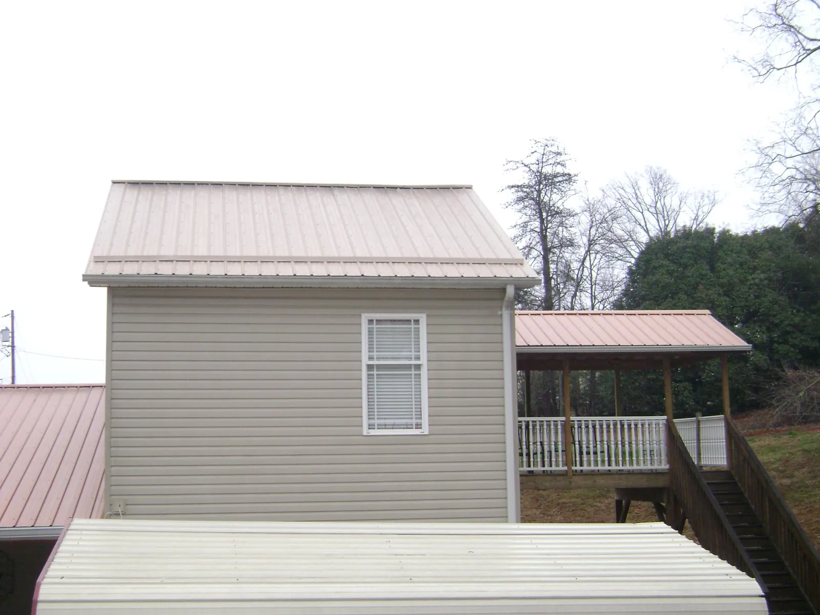 Tan metal roofs on a two story addition and attached porch, from a Roof Replacement job in Orofino