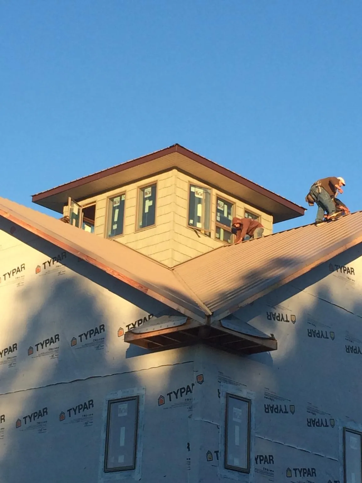 Roofers working around a rooftop cupola on a new metal roof at sunset — Roof Waterproofing in Orofino by Roofing Brothers